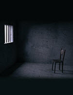 Chair in an empty cell Light through a prison window onto a wooden chair.