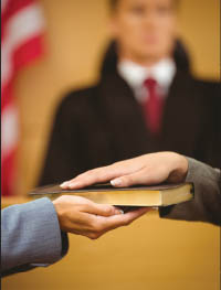 swearing-in.jpg Hands on a book showing a witness being sworn in