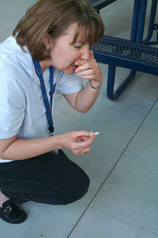 principles_of_dna_03_-_contamination.jpeg Photo of a woman bending down picking up a cigarette while holding her nose