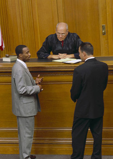 principles_of_dna_11_-_courtroom.jpeg Photo of a judge talking with a defense attorney and a prosecutor