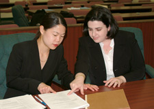 principles_of_dna_13_-_pretrial_preparation.jpeg Photo of two women in suits examining a document in court.
