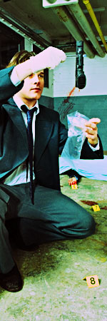 bph_moving_cases.jpeg Detective holding up a gun at a crime scene