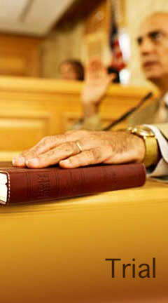 definitiontrial.jpg  Photo of a male witness placing his hand on a book before testifying. Caption reads, 'Trial'
